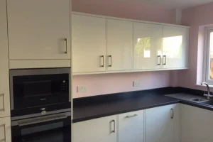 211-1920w fitted kitchen with oven, white cabinets, and black worktops